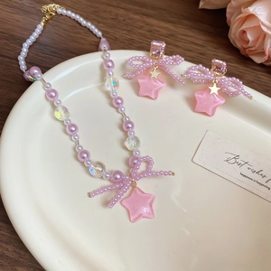 Pink pearl necklace and earring set with bow and star charms in a ceramic tray