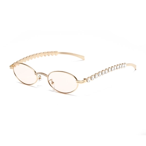 Oval gold metal sunglasses with asymmetrical heart-shaped temples and rhinestone details