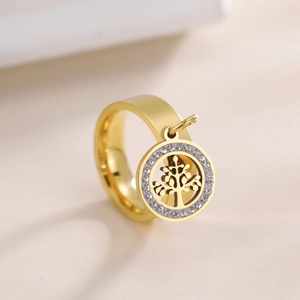Macro shot of gold stainless steel ring featuring a crystal-encrusted tree of life charm
