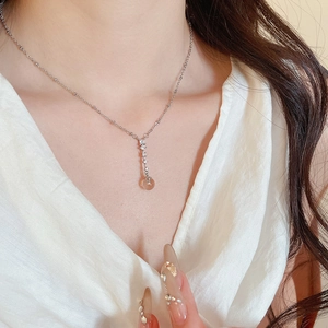 Macro view of a silver-toned necklace featuring an oval zircon pendant and a clear brown bead