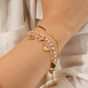Dettaglio del set di bracciali oceano con catena a serpente dorata e ciondoli a conchiglia