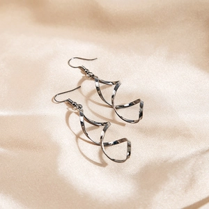 Minimalist spiral twist wave earrings in polished gunmetal grey on silk background