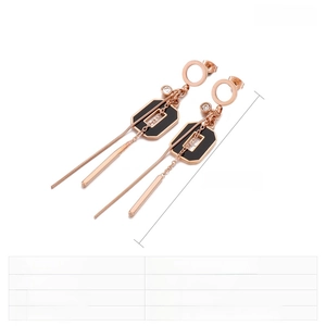 Détail des boucles d'oreilles pampilles or rose avec résine noire et chaînes en acier