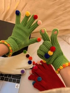 Dettaglio di guanti in maglia verdi con pompon colorati e apertura per touchscreen