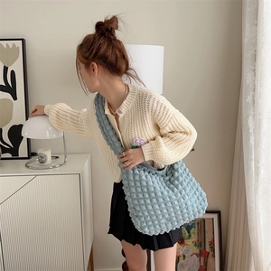 Light blue bubble fabric crossbody bag with textured surface styled on model