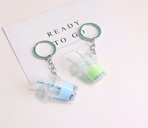 Detail of blue and green pearl milk tea keychains with striped straws on card