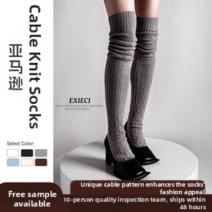 Close-up of grey cable knit over-knee leg warmers showing textured vertical patterns