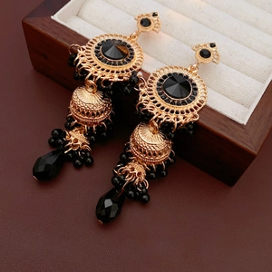 Detail view of vintage golden drop earrings with black crystals on a wooden jewelry box