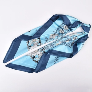 Detail of silk-like satin square scarf with blue floral prints and smooth drape texture