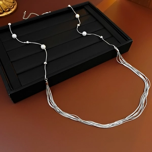 Detailed close-up of multilayer silver chain necklace with white faux pearls and metal beads