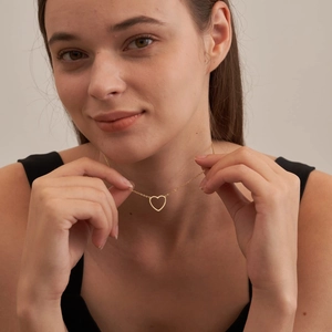 Close-up of a 18k gold heart necklace on a model showing the elegant drop and sizing