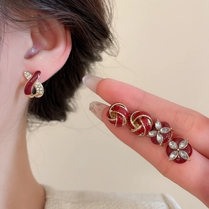 Detailed view of red enamel stud earrings with gold plating and sparkling crystal accents