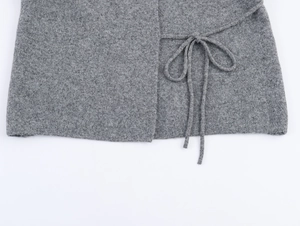 Détail d'un manteau en laine grise montrant le nœud latéral et la texture du tissu