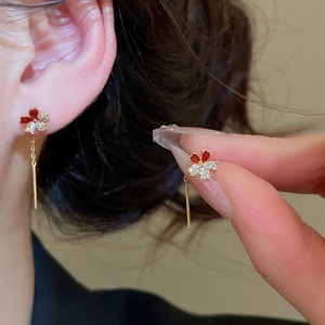 Detail of elegant 18k gold flower earrings with red enamel and sparkling zircons