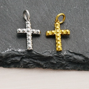 Detail von Kreuzanhängern aus Edelstahl in Gold und Silber mit körniger Textur auf Stein