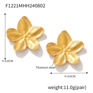 Macro detail of 3cm golden titanium steel flower earrings with brushed metal texture