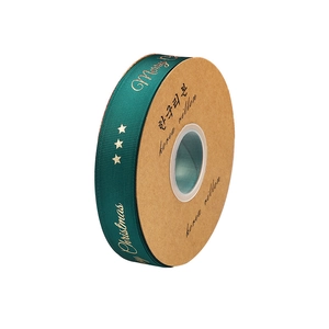 Merry Christmas green satin ribbon with gold foil lettering on a craft paper spool