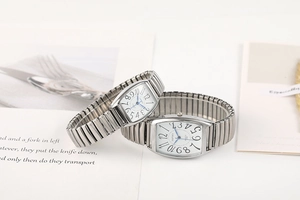 Détail de montres à quartz tonneau argentées avec bracelets extensibles sur fond blanc