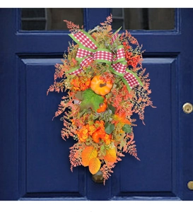 Close-up of fall door swag with orange pumpkins, maple leaves, and red plaid bow