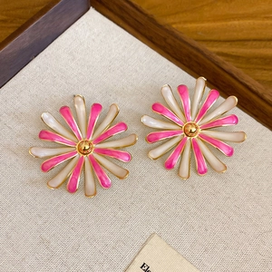 Dettaglio macro di orecchini a margherita in smalto rosa e bianco su un espositore