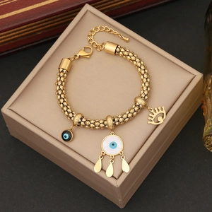 Detailed view of gold stainless steel bracelet with evil eye charms on jewelry box