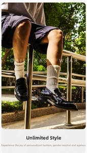 Détail de mocassins en cuir verni noir portés avec des chaussettes en coton côtelé