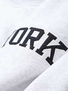 Macro detail of black YORK embroidery on light gray knit fabric for hooded sweatshirt