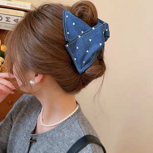 Pince à cheveux en jean bleu à motif cœur montrée sur une coiffure relevée élégante