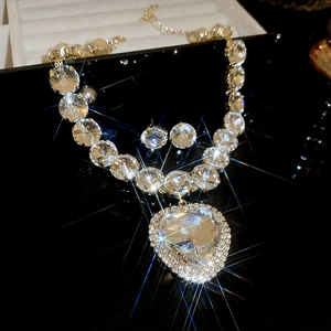 Macro view of crystal heart pendant and matching earrings set on a dark background