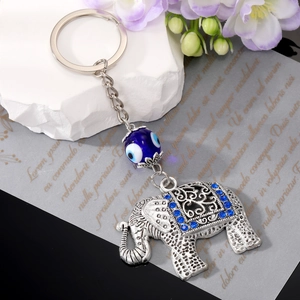 Vintage silver elephant keychain with blue evil eye bead and rhinestones on aesthetic background