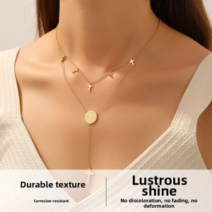 Close-up of double layer gold stainless steel necklace with cross and medal charms