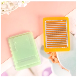Detailed view of miniature dollhouse BBQ grill with yellow metal grate and mint green base