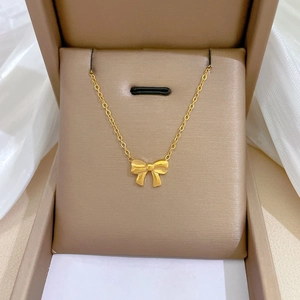 Detailed view of a gold bow pendant necklace elegantly presented in a brown jewelry gift box