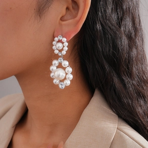 Elegant silver circle earrings with pearls and zircon crystals worn by a female model