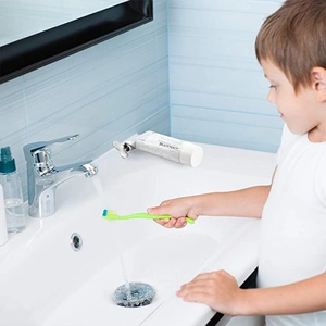 Manual metal toothpaste squeezer shown in a bathroom setting for daily oral care usage