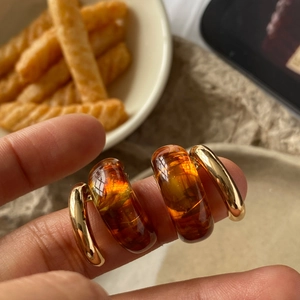 Macro detail of amber resin and polished gold metal C-shape earring set
