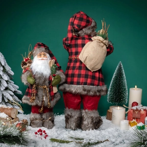 Standing Santa Claus figurines in red plaid outfits with ski gear on artificial snow