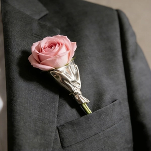 Nahaufnahme eines silbernen Boutonniere-Halters am Anzug mit einer frischen Rose