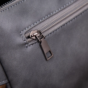 Macro view of metallic zipper detail on textured grey leather street style chest bag