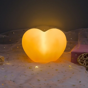 Macro shot of heart-shaped night light emitting warm glow on white star tulle fabric
