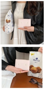 Close-up of pink short wallet featuring bow embroidery and pearl accents held by a model