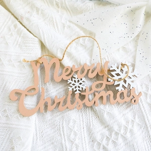 Detail of wooden Merry Christmas sign with white snowflakes on knitted fabric
