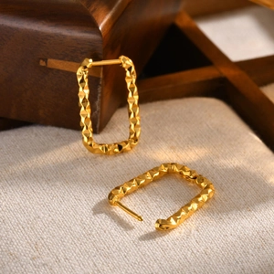 Macro shot of gold plated rectangular hoop earrings with geometric diamond cut texture
