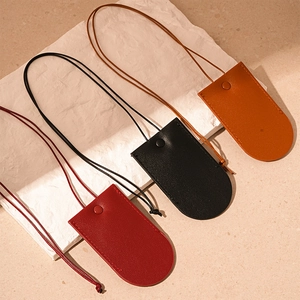 Three leather key case necklaces in red, black, and brown with pebbled texture and snap buttons