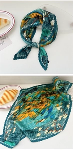 Detail of pleated silk scarf with blue and yellow abstract print and accordion texture
