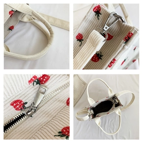 Detail of corduroy bag handles, strawberry embroidery, metal hooks and zipper closure