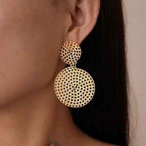 Gros plan de boucles d'oreilles dorées en maille tissée sur un mannequin avec fini métal