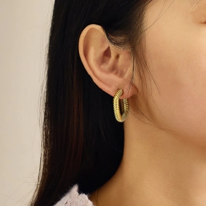 Close-up of gold twisted rope hoop earrings worn to show style and size detail
