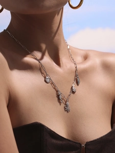 Detail of silver chain necklace with sea charms like shell and seahorse on model