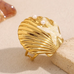 Macro detail of 18K gold starfish and shell ring with small pearls and ivory resin